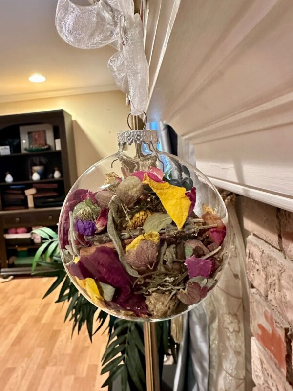 herb and flower ornament in a glass disc hanging from a fireplace mantle