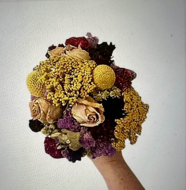 a hand holding a colorful dry floral bouquet on a white background