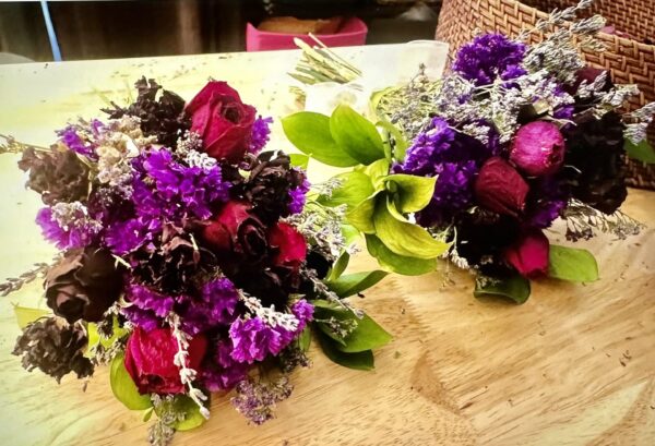 two purple dried flower bouquets on a wood table